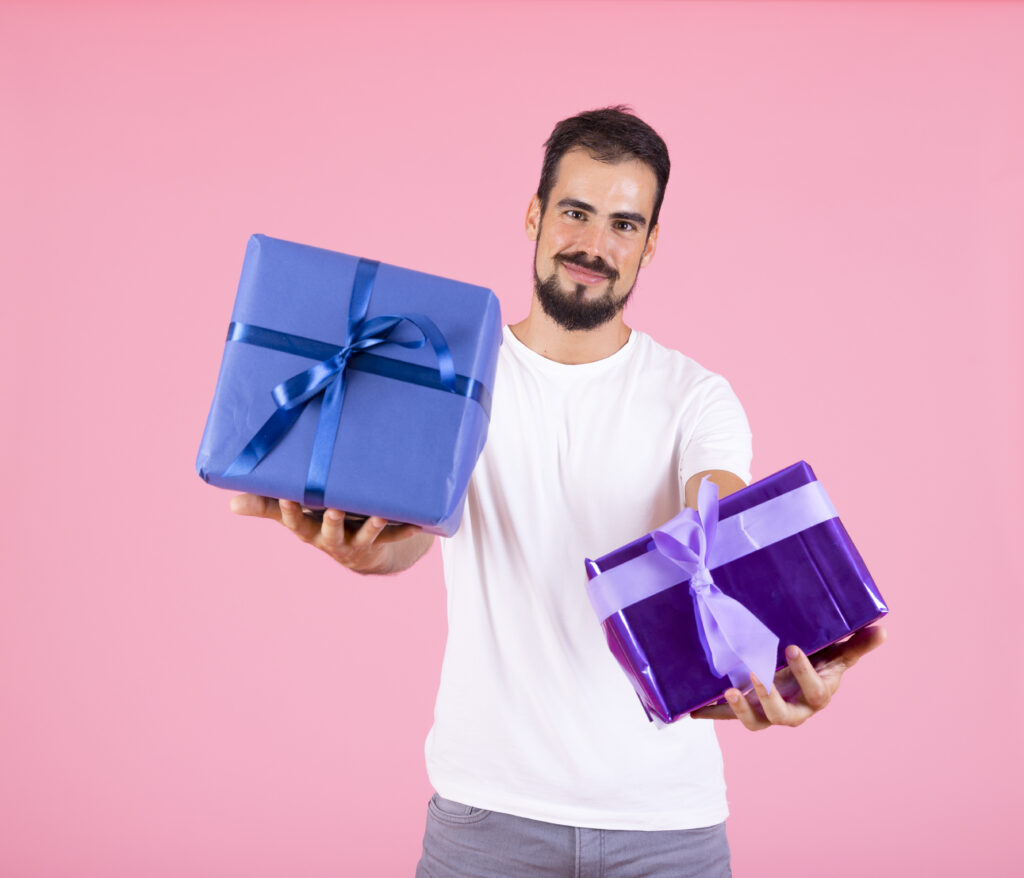 Home man offering wrapped present pink background